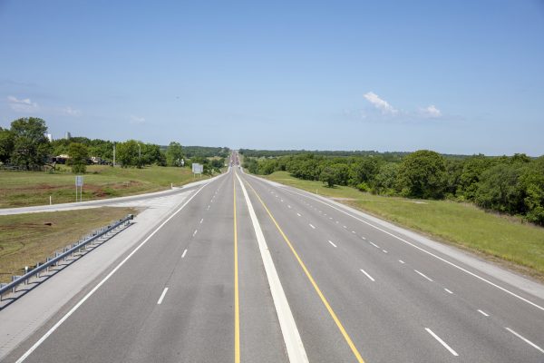 Highway in the American countryside, driveway with lane, white yellow line, sign, nature, road infrastructure, blue sky background.